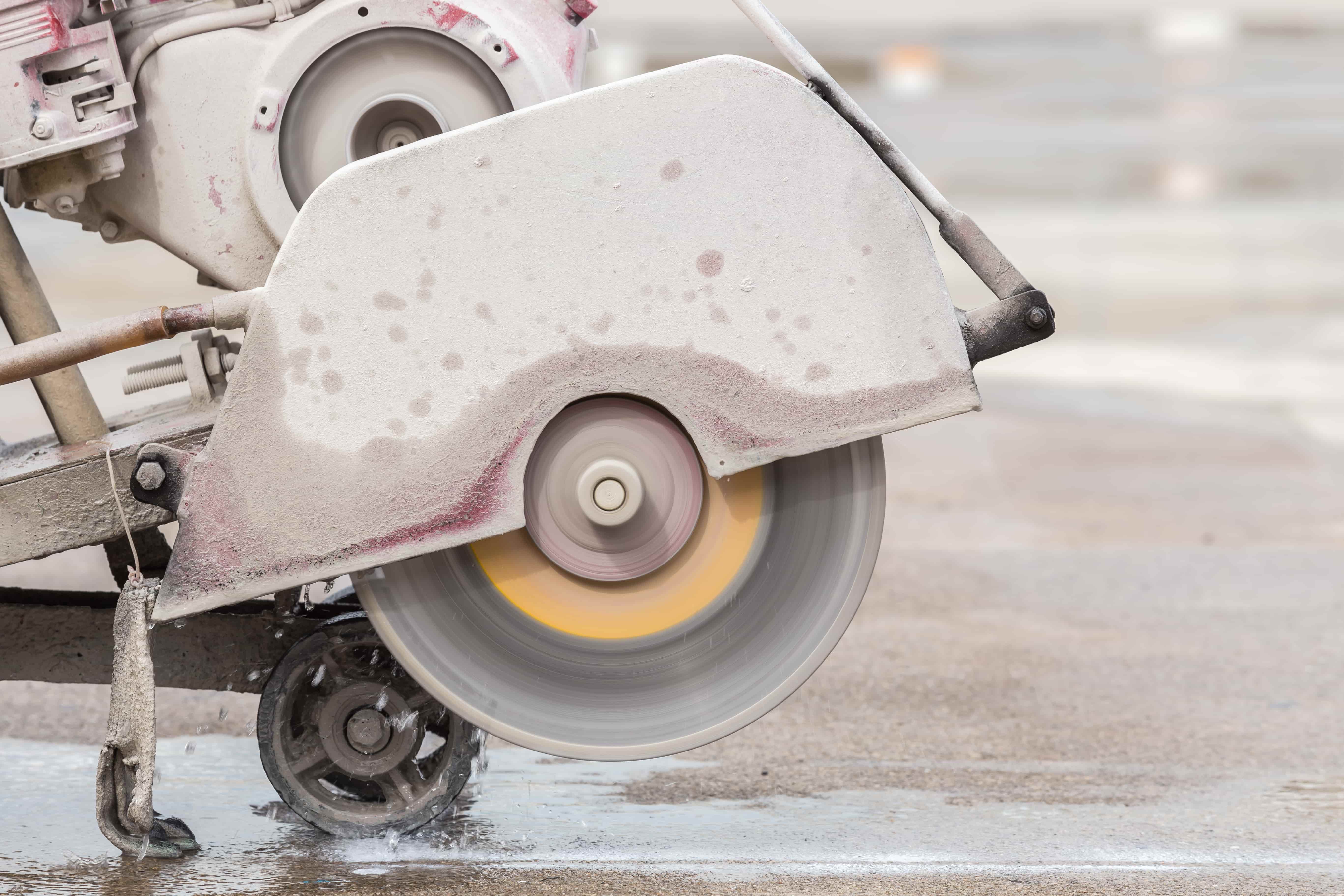 worker cutting concrete road with diamond saw blade machine min 1